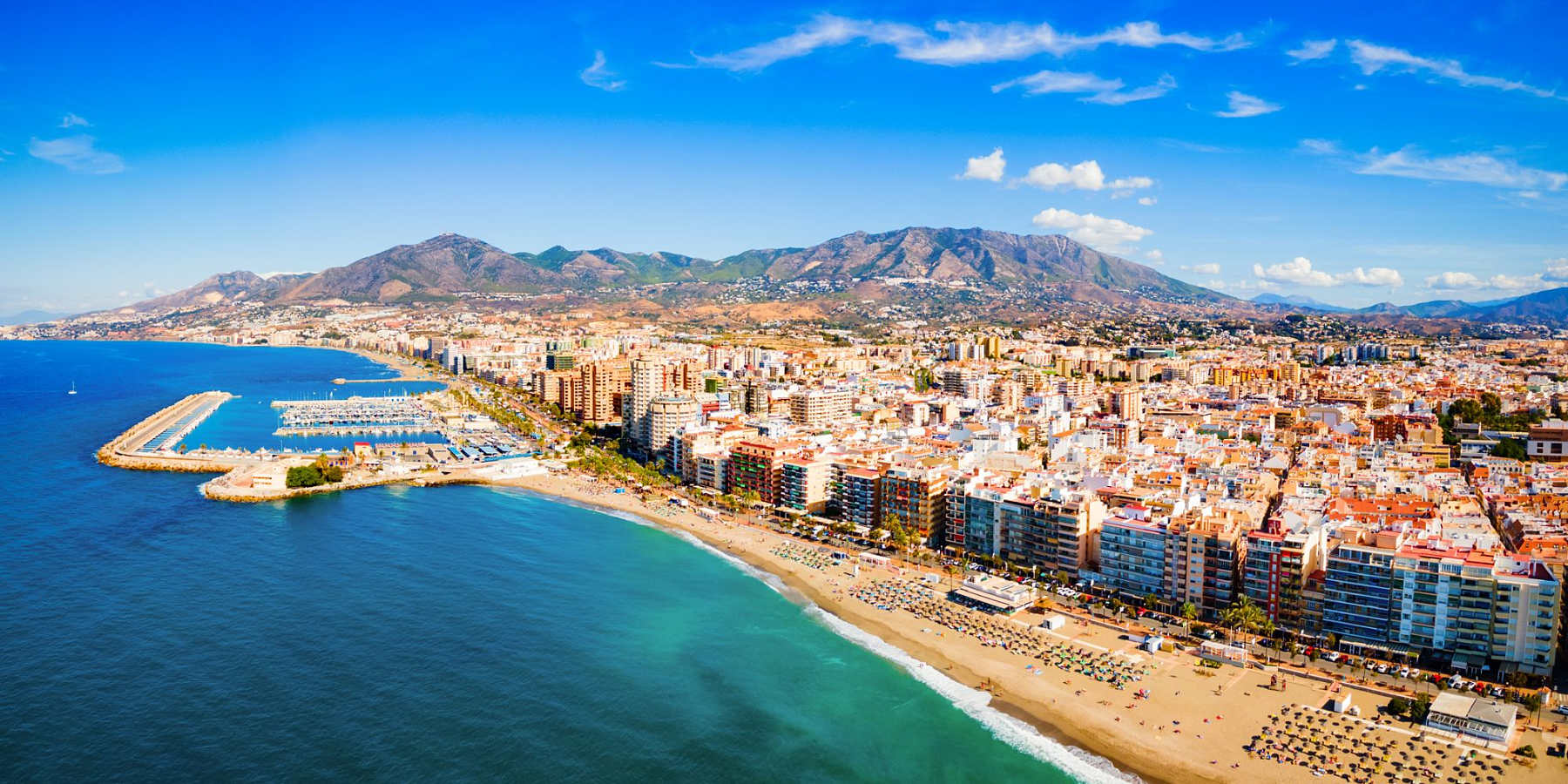 Flygbild över stranden, hamnen och staden Fuengirola på Costa del Sol