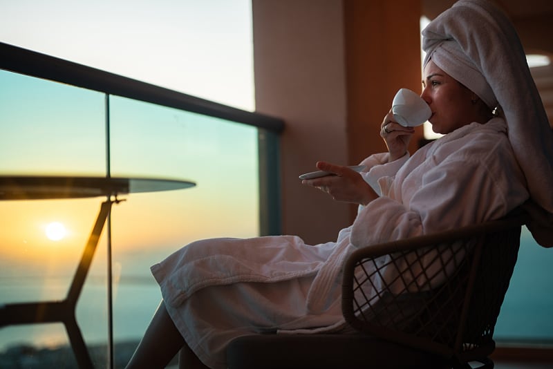 Woman enjoying sunset view from sunny terrace with coffee