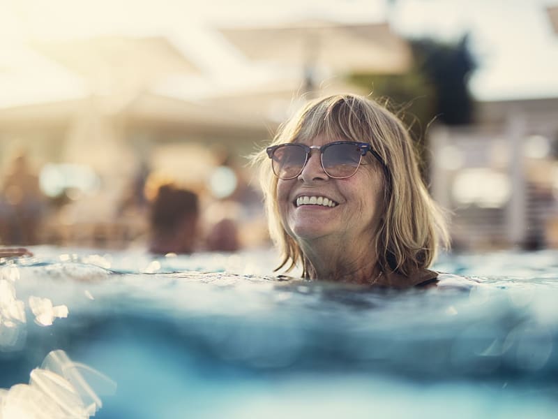 Lykkelig kvinne som nyter utendørs basseng i Spania