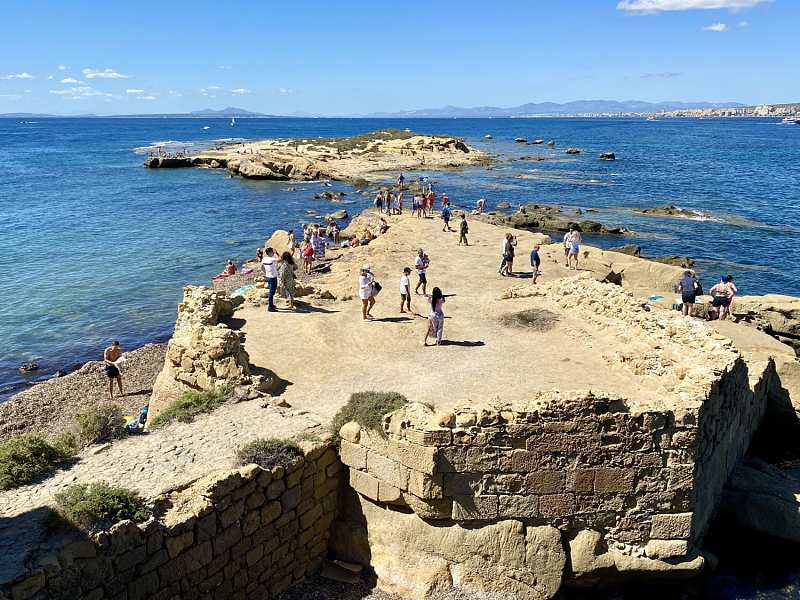 Klippfull kystlinje på Tabarca-øyen med krystallklart vann og Illot de la Cantera