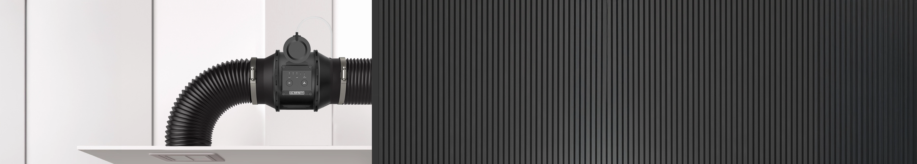 Automatic inline booster fan connected to black flexible ducting installed against a white wall and corrugated metal panel.