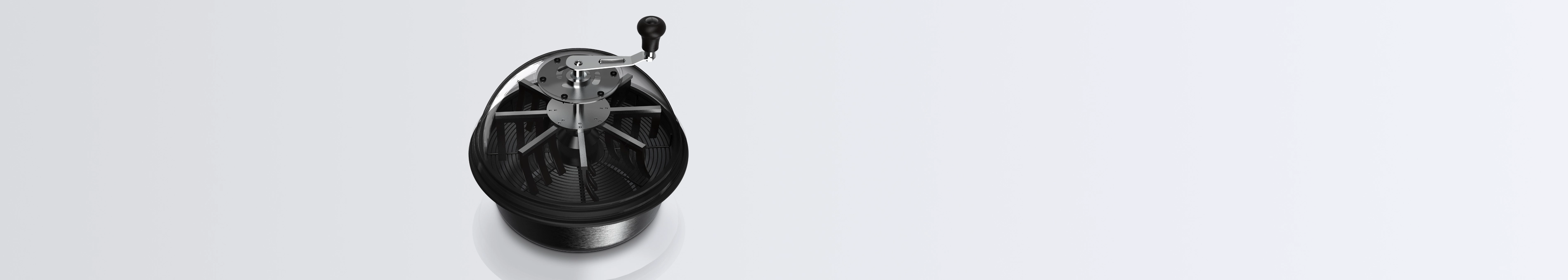 A hand-cranked bowl leaf trimmer featuring a clear dome top that reveals internal black silicone fingers and a metal grate, resting on a bright white reflective surface.