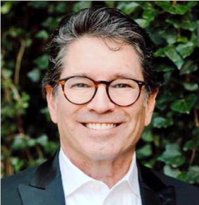 Headshot of John Ferrone, a man with dark hair and glasses, smiling and wearing a blazer.