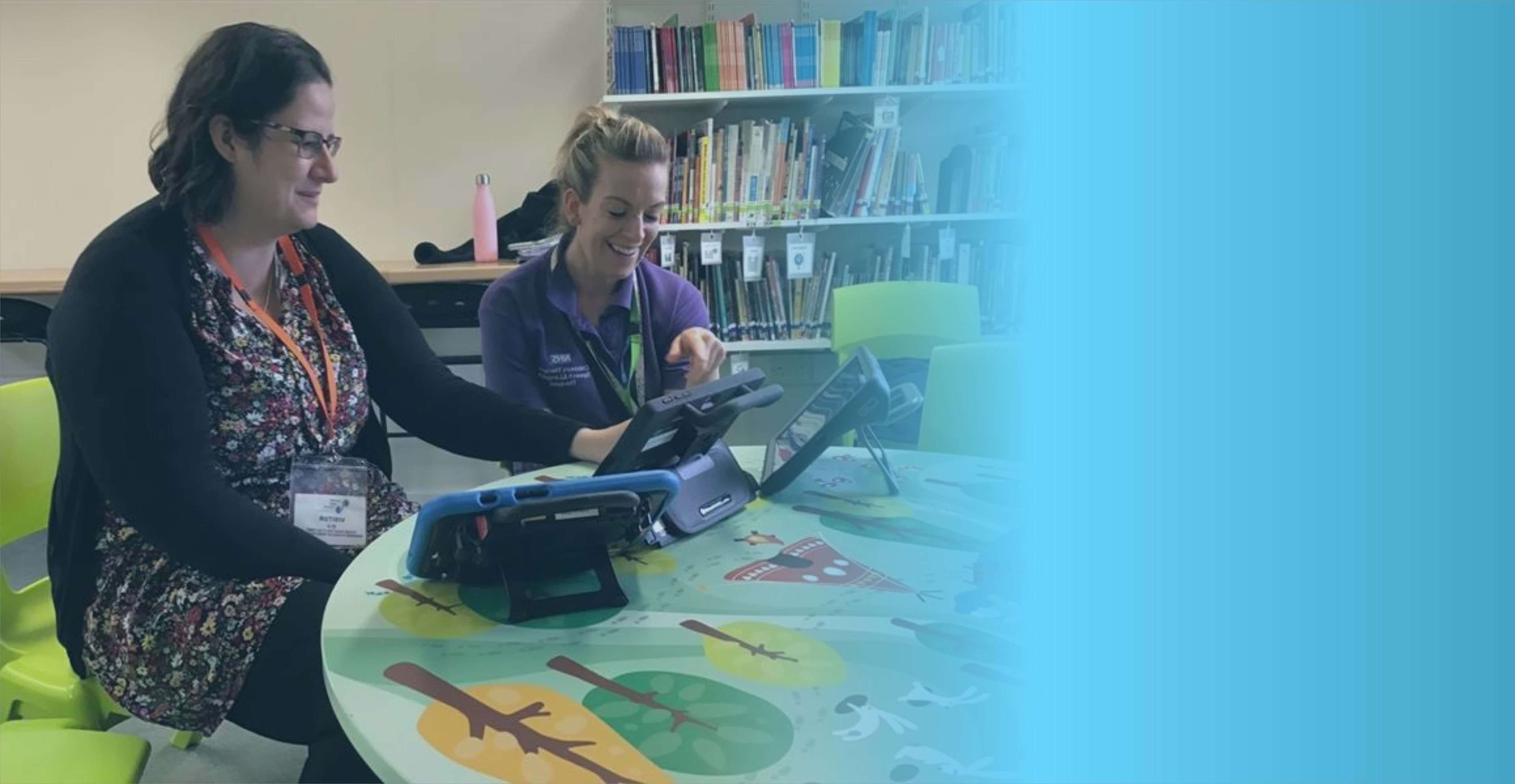 Two clinicians looking at an AAC device