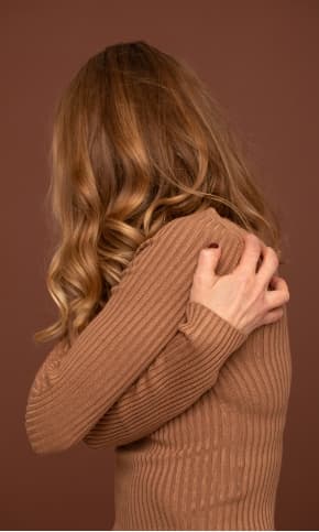 A woman hugging herself as she turns away from the camera