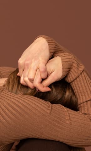 A women, kneeling, with her head in her hands
