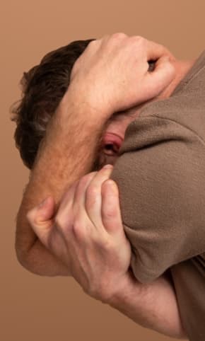 A man, collapsing his head into his hands.