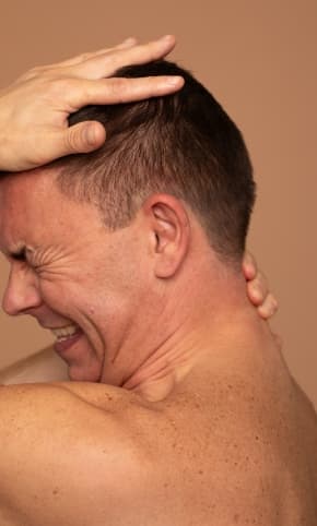 Someone grimacing with their head in their hands