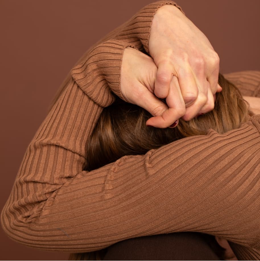 A women, kneeling, with her head in her hands