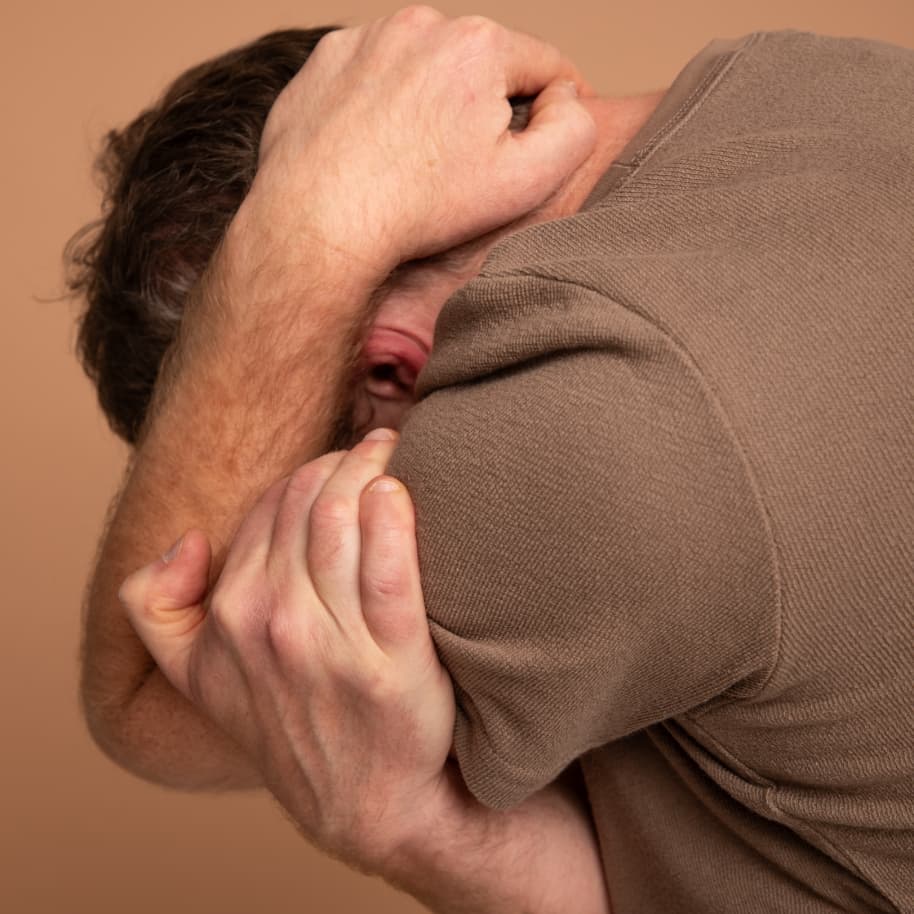 A man, collapsing his head into his hands.