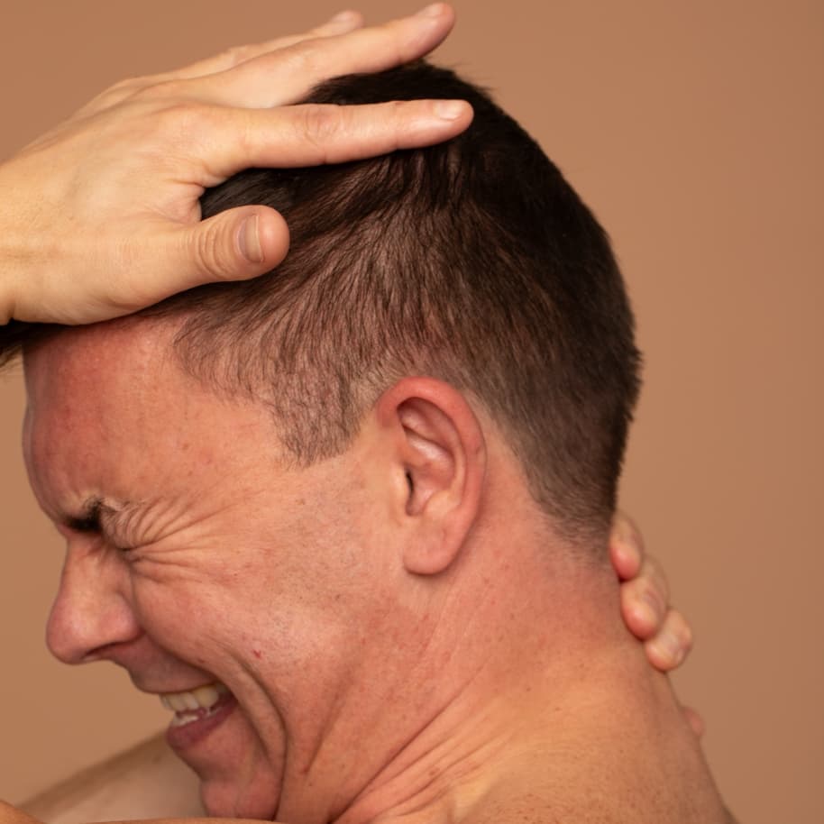 Person clutching at their head and grimacing.