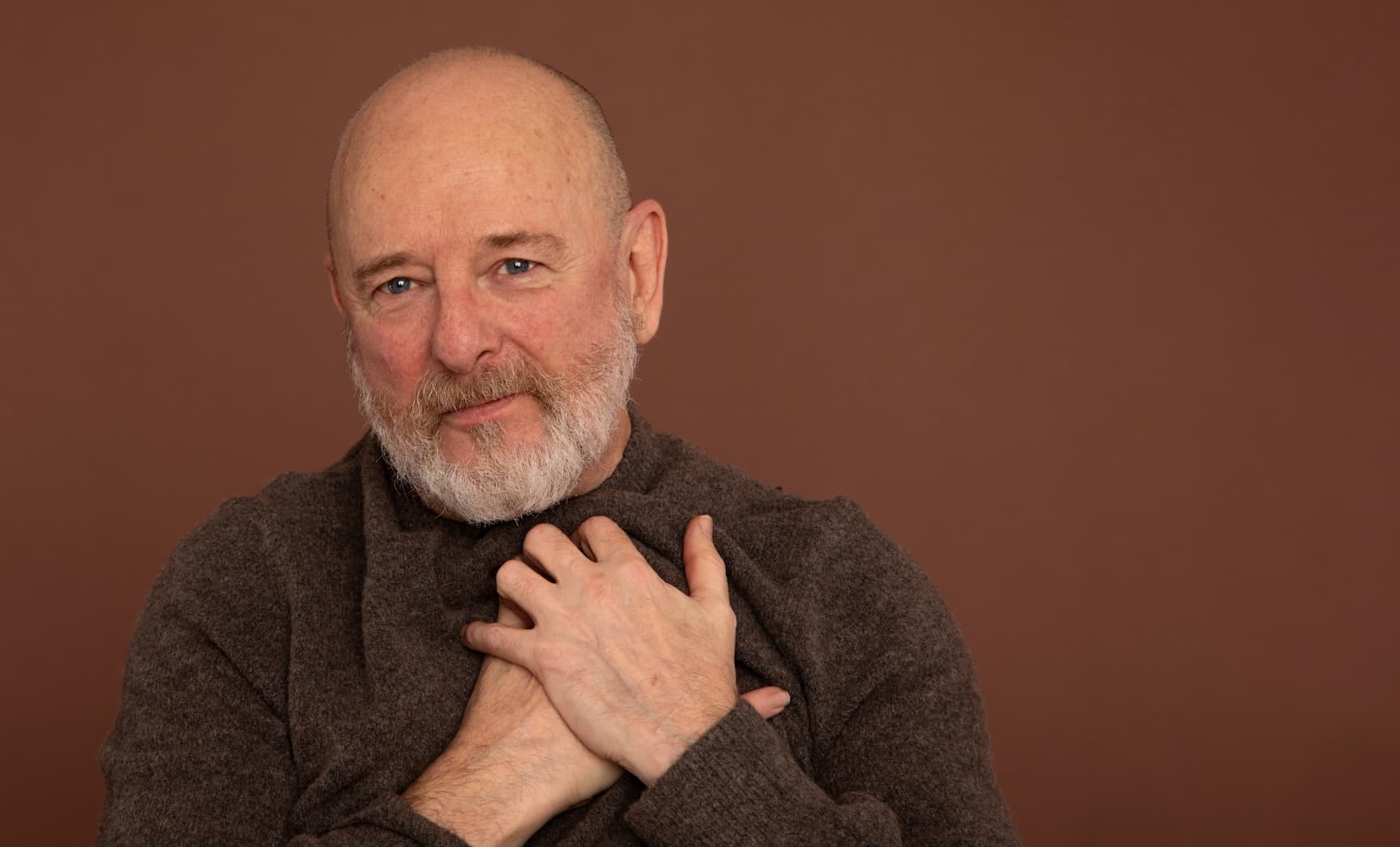 Man holding his heart and looking towards the viewer.