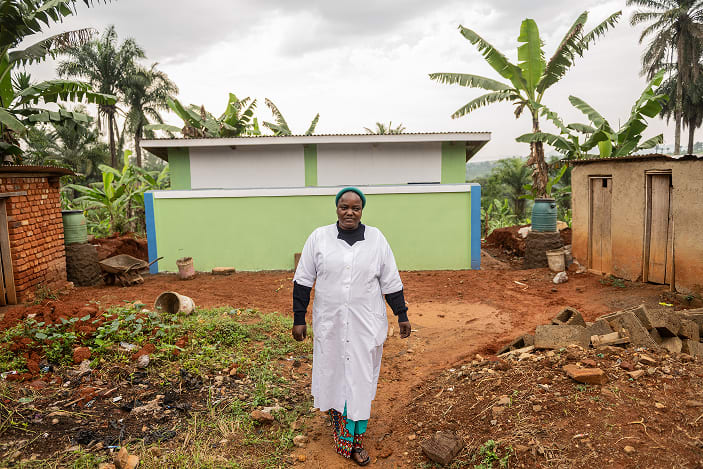 Soeur CHARLOTTE VIVE, Infirmière Titulaire Du Centre De Santé Notre Dame De La Charité Maternelle, devant les latrines construites par ACF - Mongbwalu