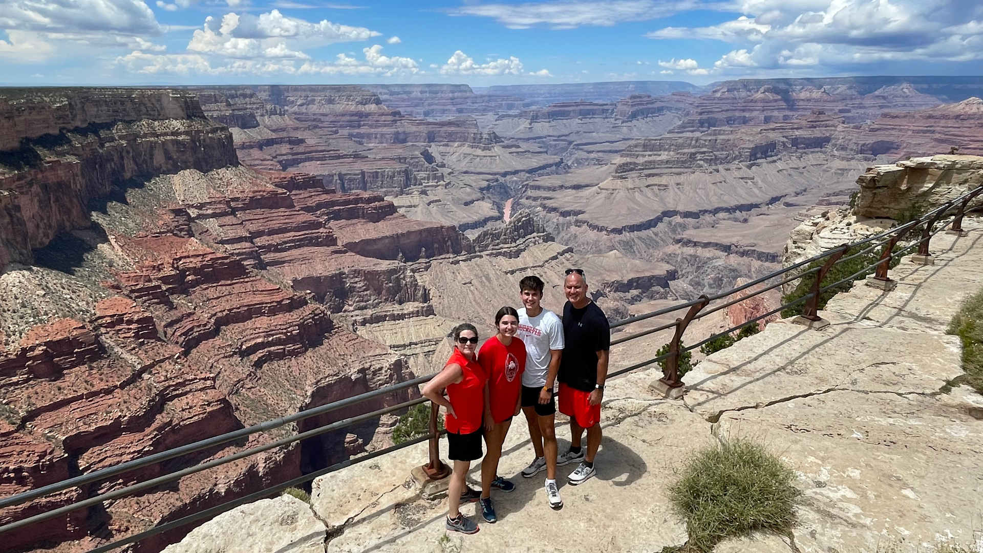 A family of four poses at a viewpoint overlooking the Grand Canyon in Grand Canyon National Park
