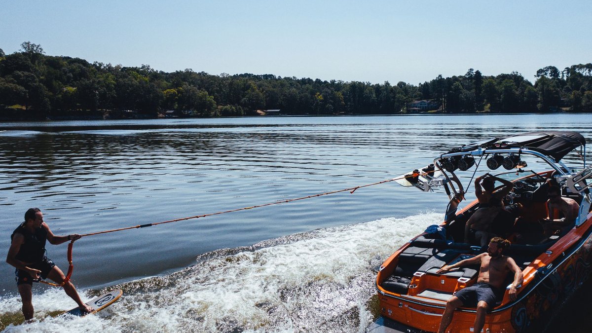 Nigerian youth channel punk spirit at Wake Up! 2 Anonymous male traveler on wake board holding rope of motor boat on foamy river while practicing extreme sport.