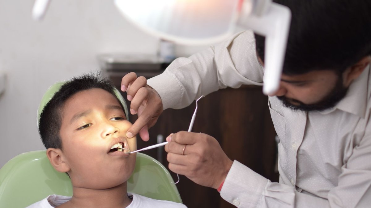 A dentist checks a child's teeth in a well-lit dental clinic, focusing on oral care.