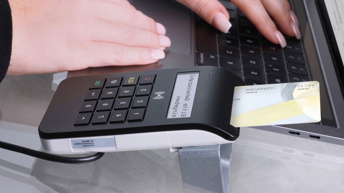 Close-up of contactless payment using laptop and card reader, showcasing modern office technology.