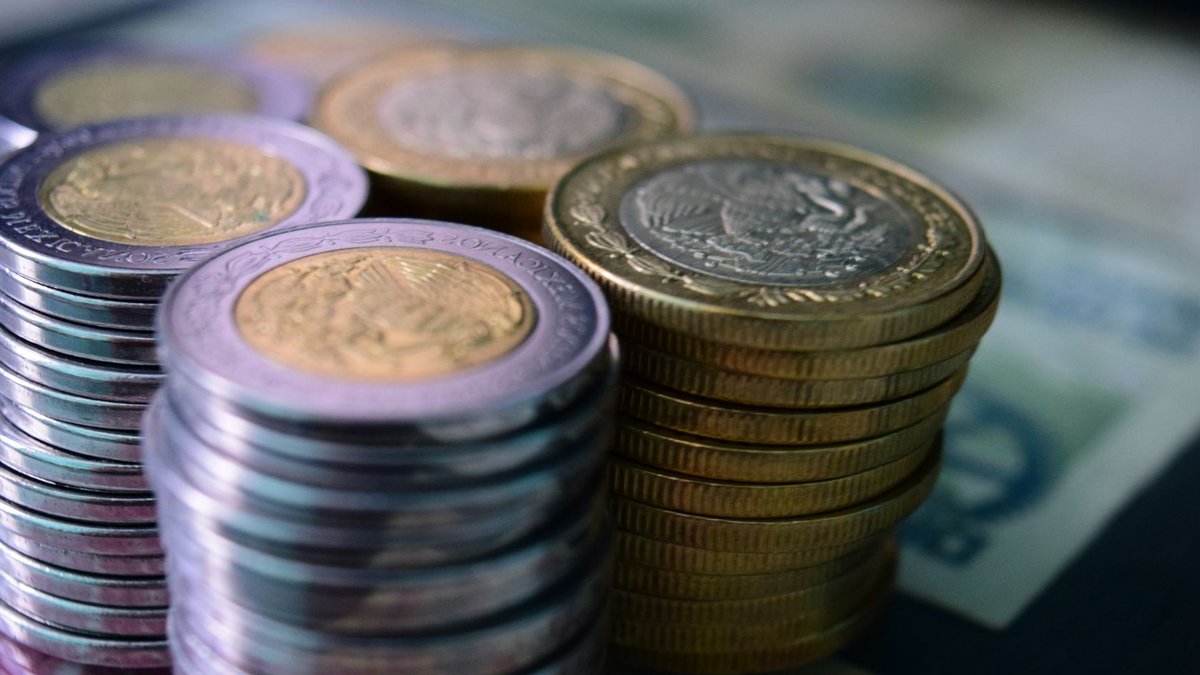 Australian household wealth reaches record high Close-up of stacked gold and silver coins on various currency notes, symbolizing wealth and savings.