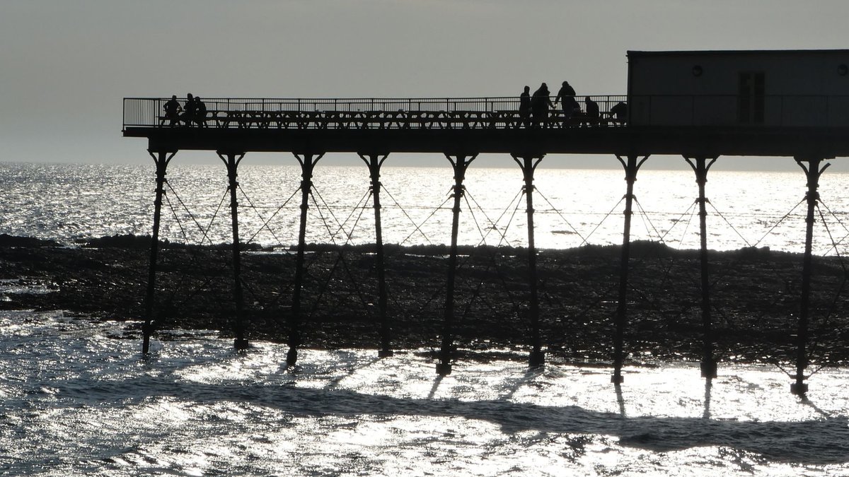 University-backed grants fuel three Welsh startups People silhouetted on Aberystwyth pier at sunrise, reflecting over the sea.