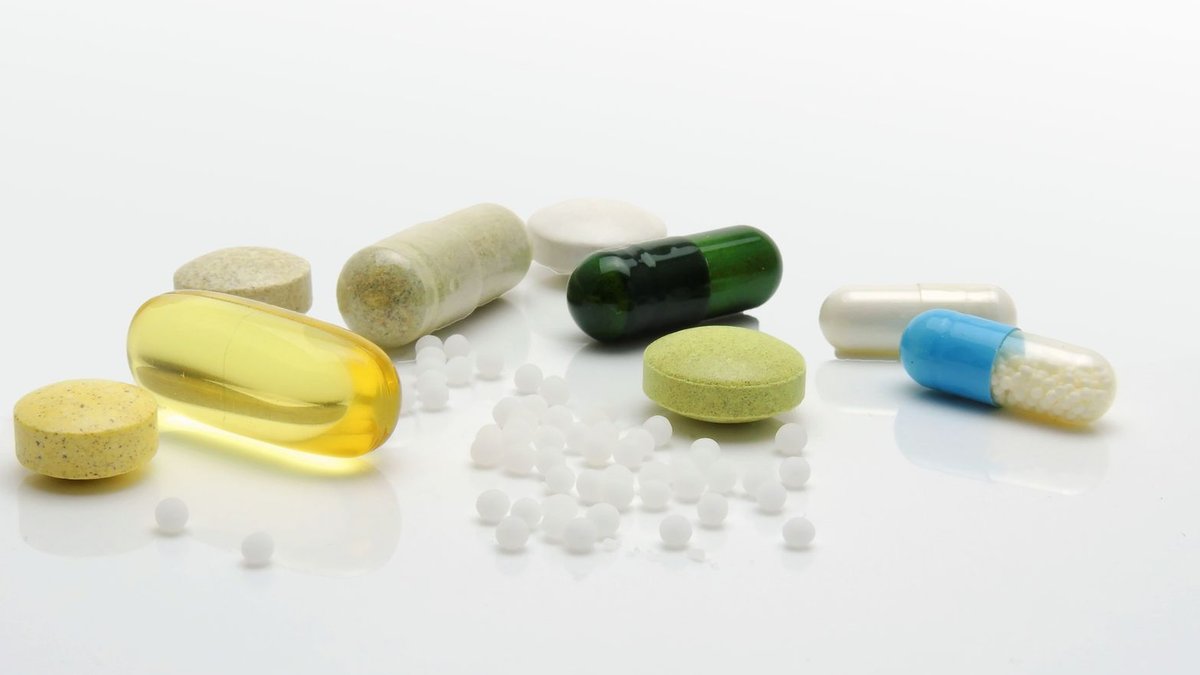 GE HealthCare tests AI to speed up cancer treatment workflows Close-up of various pills and capsules on a white surface, representing healthcare.