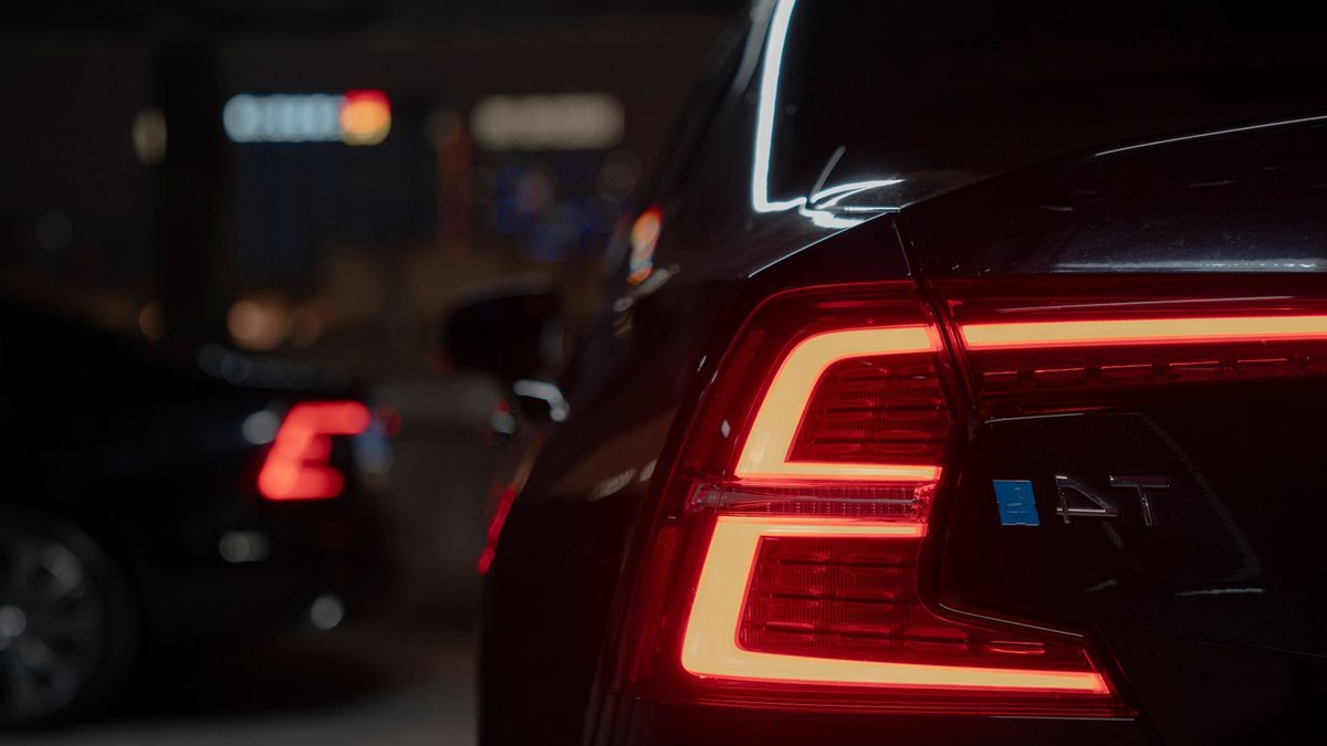 Dark moody image of a car tail light glowing vividly in a dimly lit parking area at night.