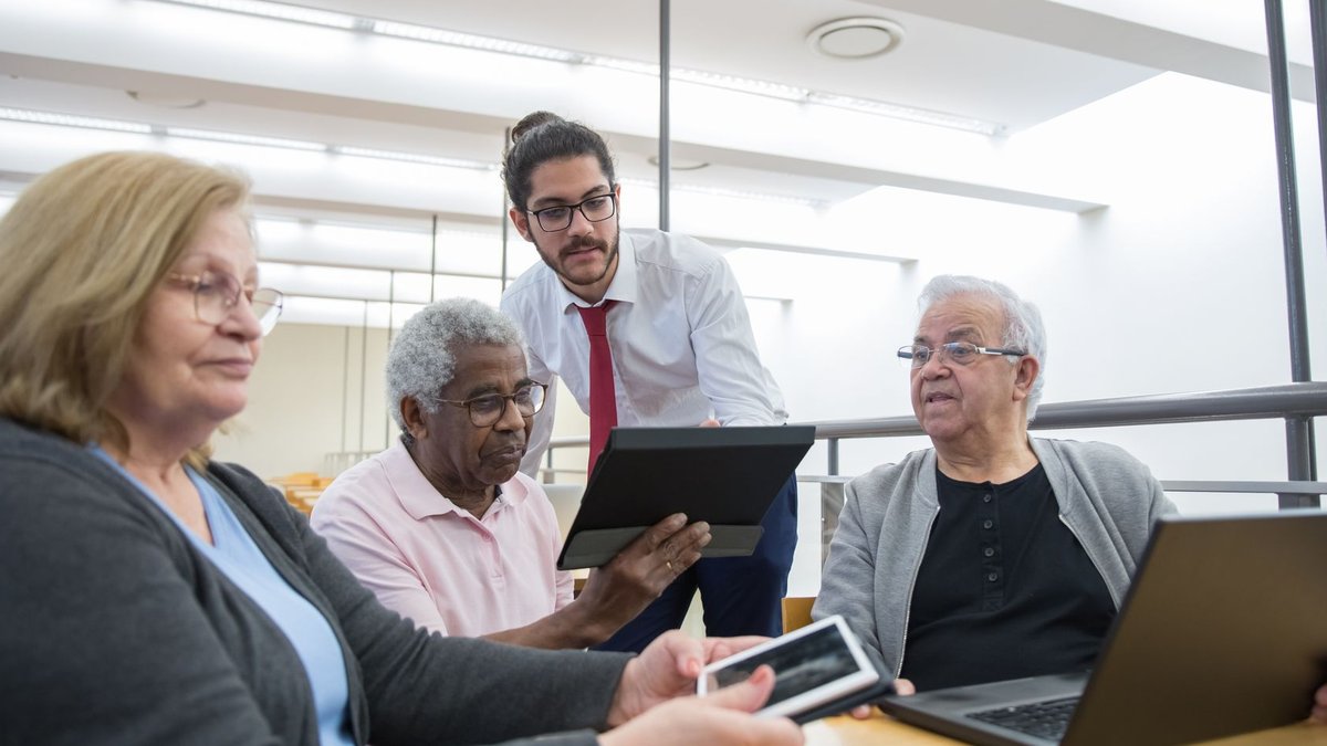Americans Use AI Despite Growing Skepticism Elderly individuals engage in a digital learning workshop, embracing modern technology in a library setting.