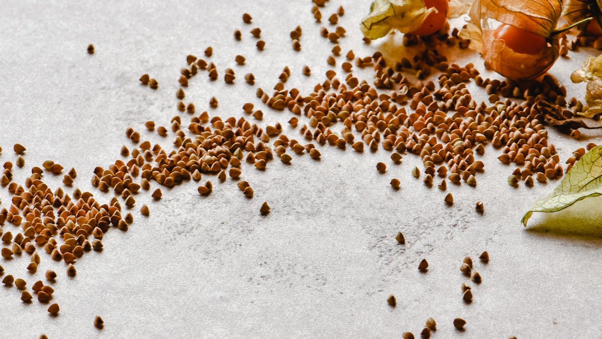 Scattered raw buckwheat grains and physalis showcasing a healthy, natural theme.