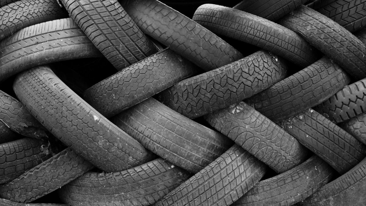 A black and white image showcasing a pile of old rubber tires intricately stacked, creating a textured pattern.