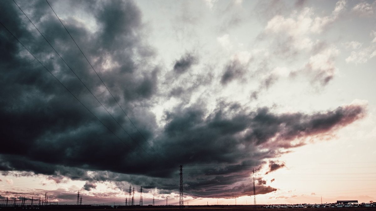 A stunning sunset with dark, dramatic clouds and power lines creating a moody landscape.