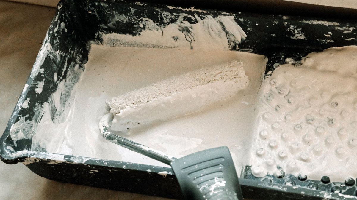 Manchester charity center gets fresh paint boost from local volunteers A paint roller dipped in white paint in a plastic tray, ideal for home renovation projects.