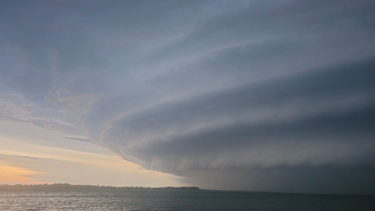 Striking view of layered storm clouds over ocean waters during a sunset.
