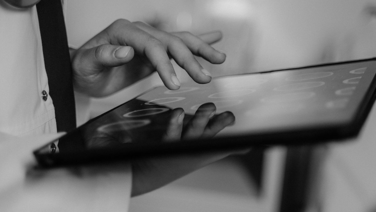 Healthcare Adopts Software Platforms for Seamless Data Integration Close-up of a doctor's hand using a touchscreen tablet, highlighting digital healthcare technology.
