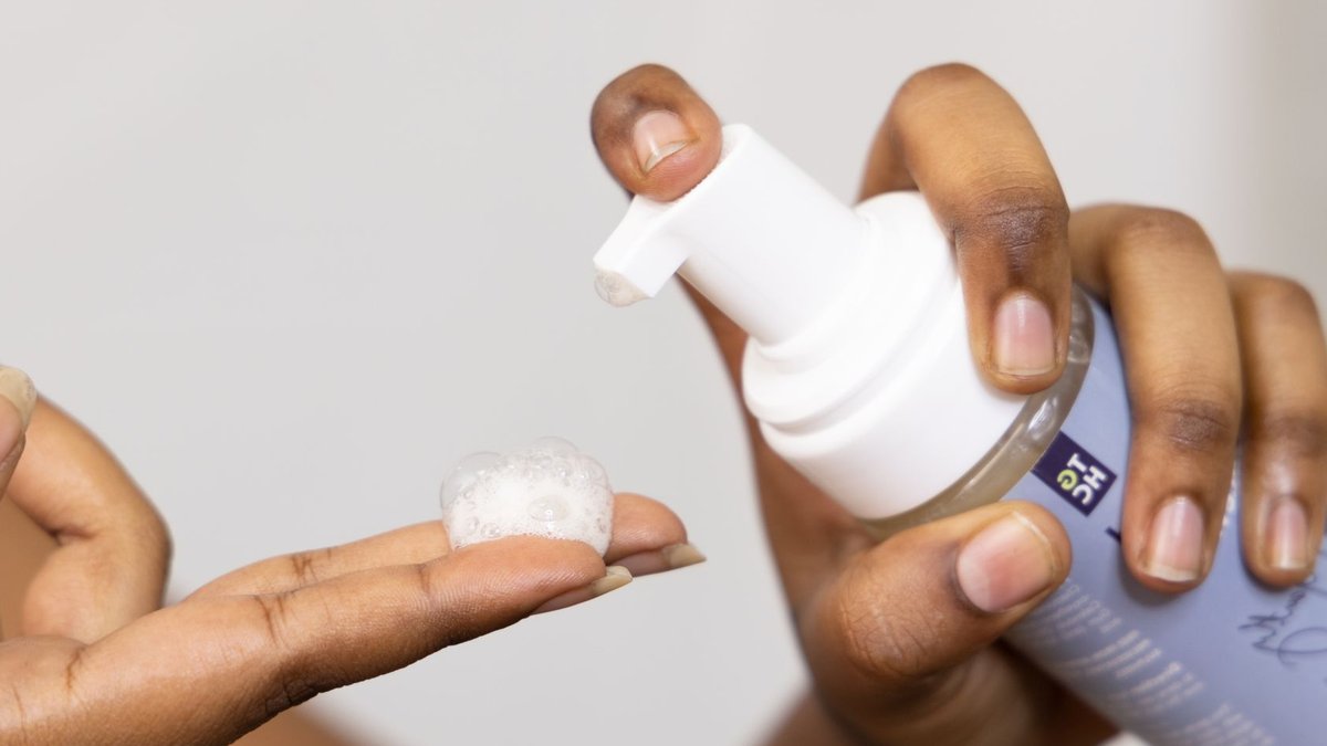South Africans can win SKNLOGIC skincare kit Close-up of hands dispensing soothing foaming face wash, ideal for sensitive skin care.