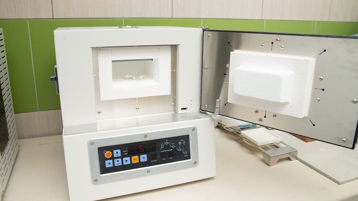 Interior of modern light dental clinic with white thermal oven with dental implants inside.