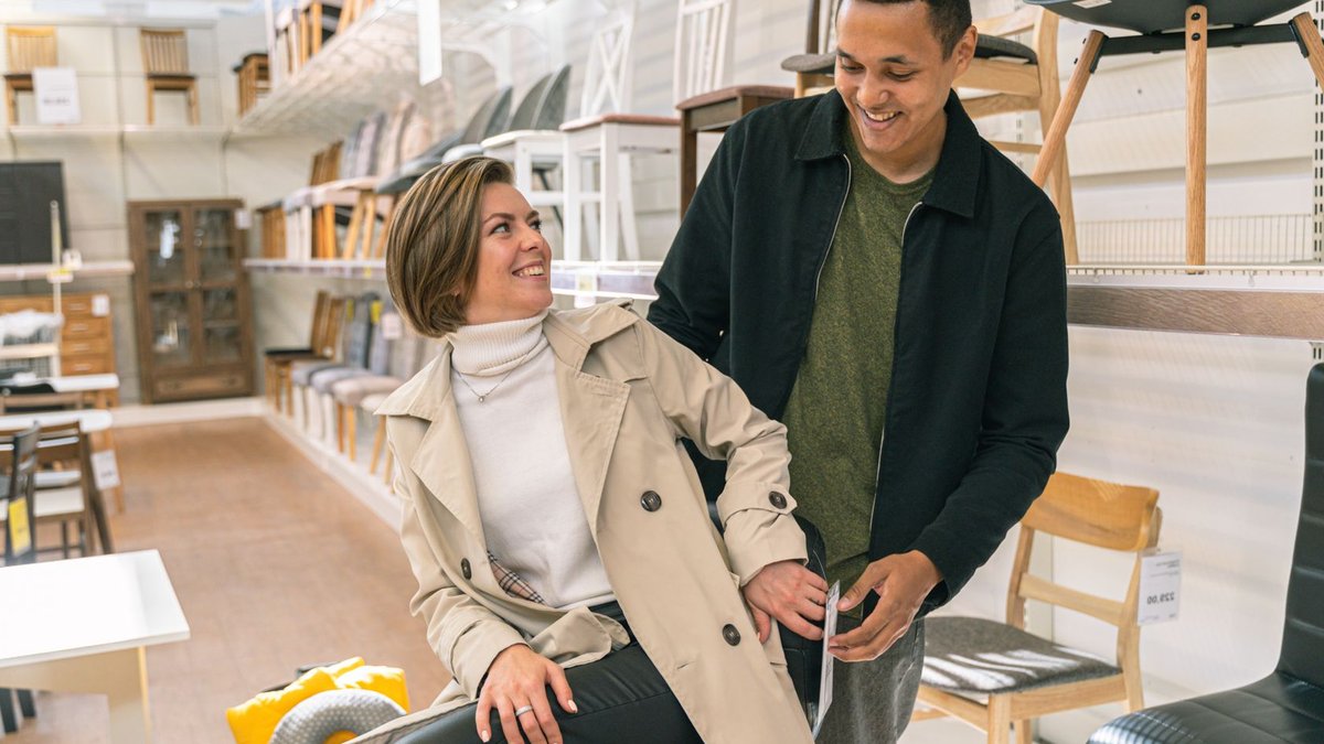 A couple happily explores a furniture store filled with stylish chairs and decor, showcasing modern lifestyle.