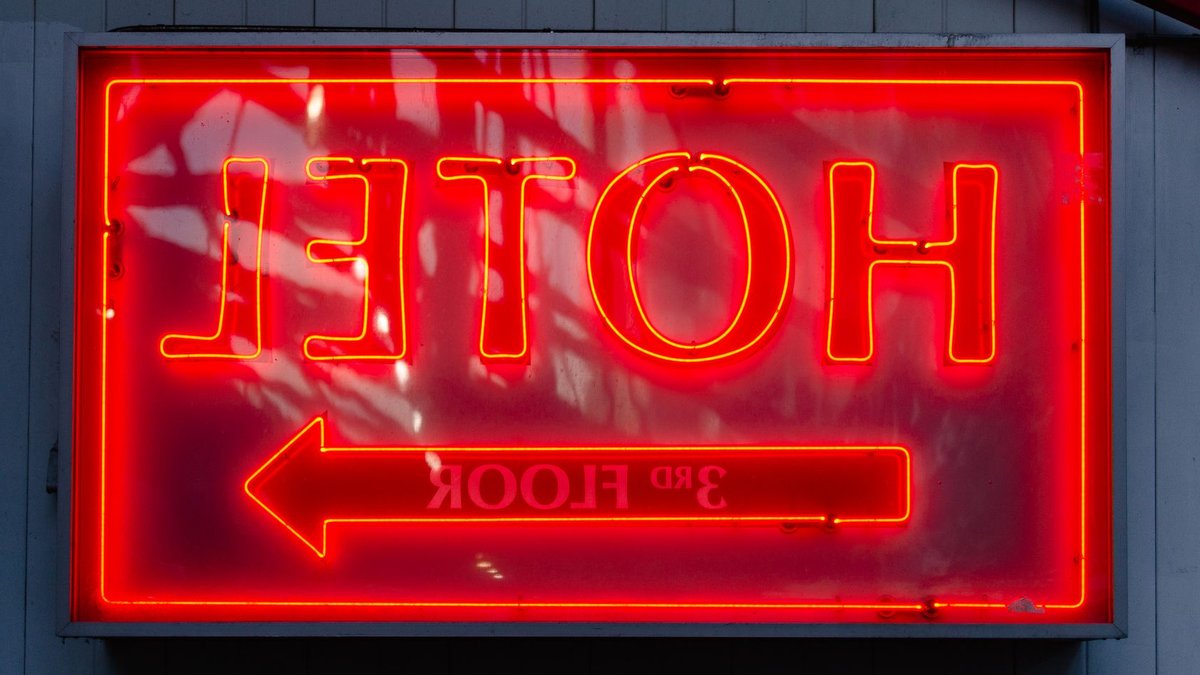 Close-up of a neon hotel sign indicating the 3rd floor, vibrant in red.