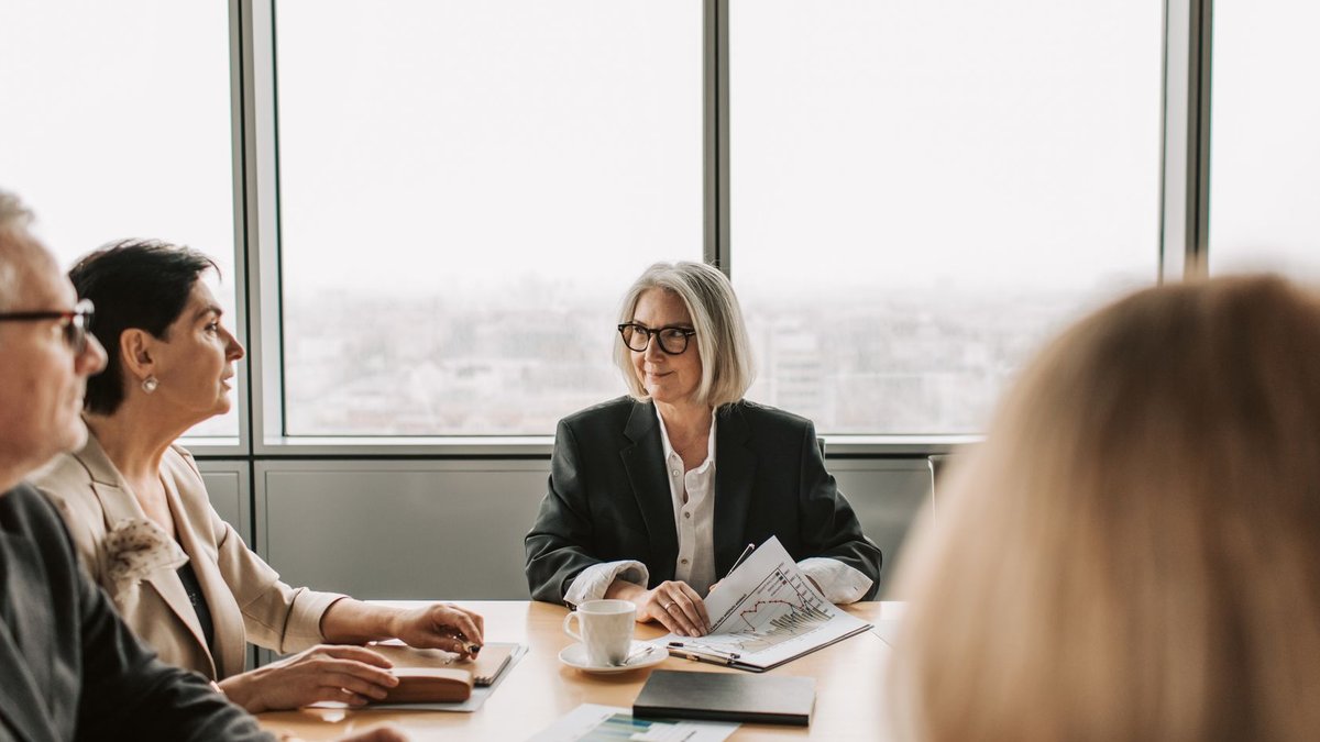 A group of professionals engaged in a business meeting inside a modern office boardroom.