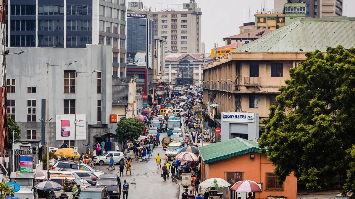 Pedestrians walk between office buildings in the Central Business District of Lagos, Nigeria. Image.