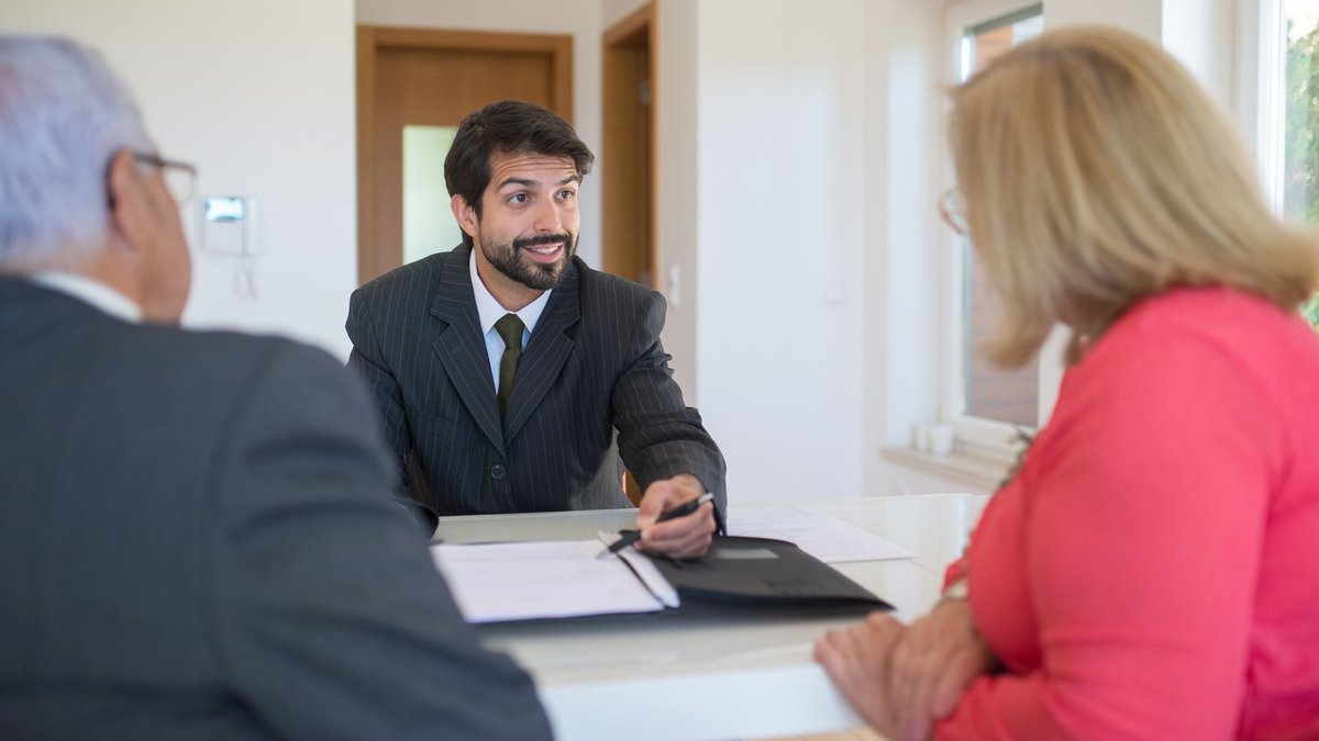 A real estate agent discussing a deal with senior clients in an office setting.