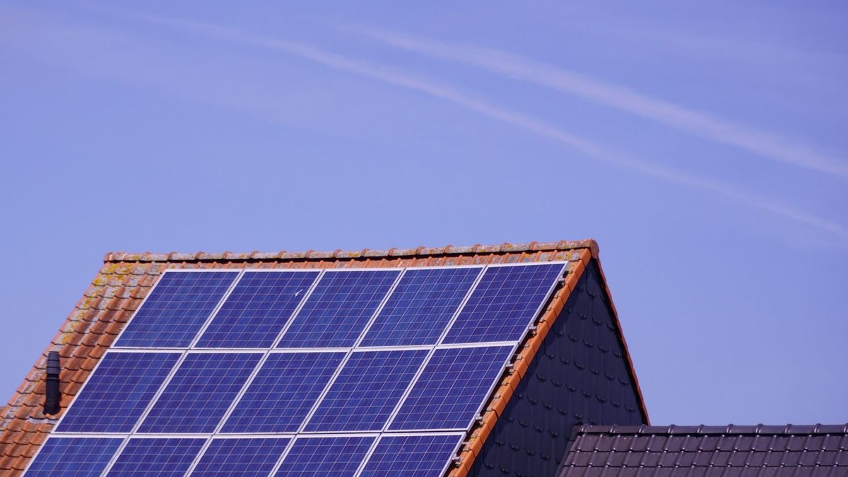 Close-up of solar panels on a tiled rooftop under a clear sky, showcasing renewable energy.