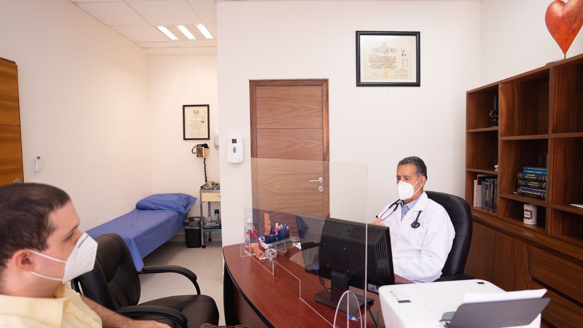 Older AML patients shift from fitness to curability in treatment Doctor and patient with masks in medical clinic, emphasizing healthcare safety.