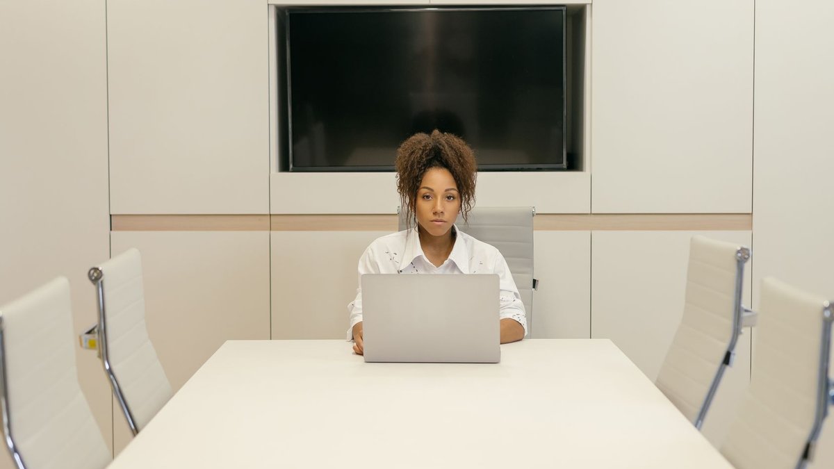 HR Leaders to Discuss Change Barriers Online Professional woman using a laptop in a sleek conference room setting, focused and efficient.