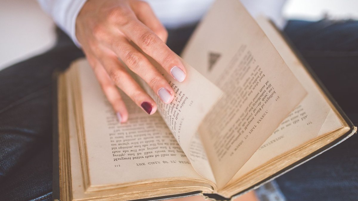 Book explores ancient poetry for leadership insights A woman flips through the pages of an old book, focused on reading and learning.