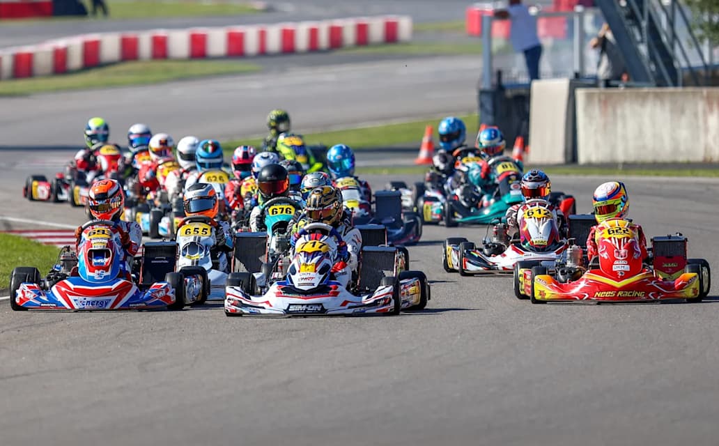 A close pack of kart racers on an asphalt circuit