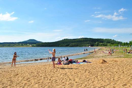 Vor der Kulisse der Landeskrone lässt es sich am Berzdorfer See am Strand entspannen