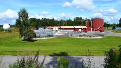 Bland nyklippt gräs och skog står vattenbassänger och rödmålade avloppsreningsanläggningar.