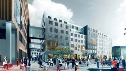 The new Carlsberg City District, with a distinctly silver coloured building at the forefront, connected with other buildings and with a plaza in front.