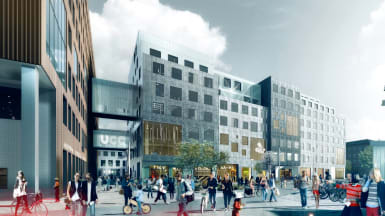 The new Carlsberg City District, with a distinctly silver coloured building at the forefront, connected with other buildings and with a plaza in front.