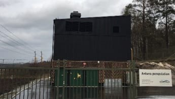 Solgryningen lyser upp Antuna pumpstation och en bil intill, samt naturen i bakgrunden.