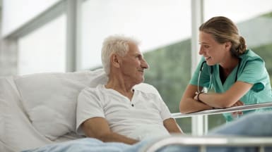 Picture of an elderly man socializing with a hospital worker.